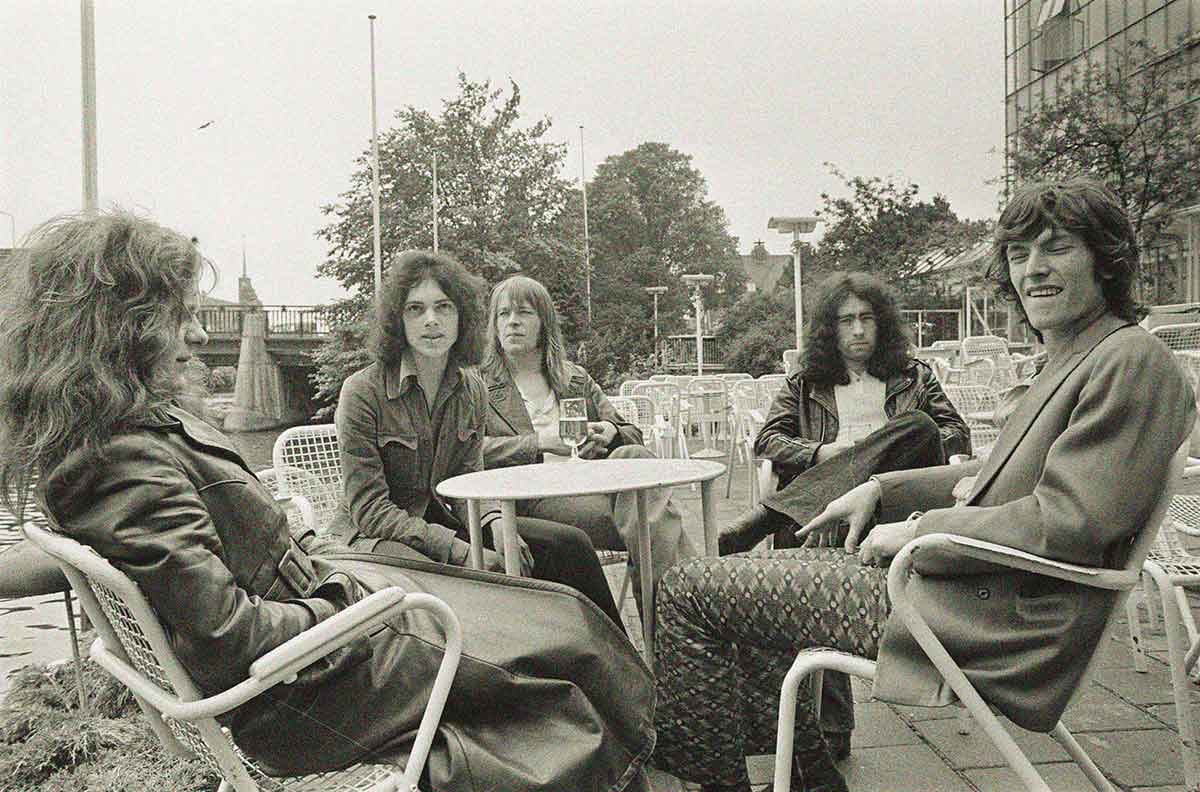 Photographie représentant les membres du groupe Free assis autour d'une table d'un café en extérieur.